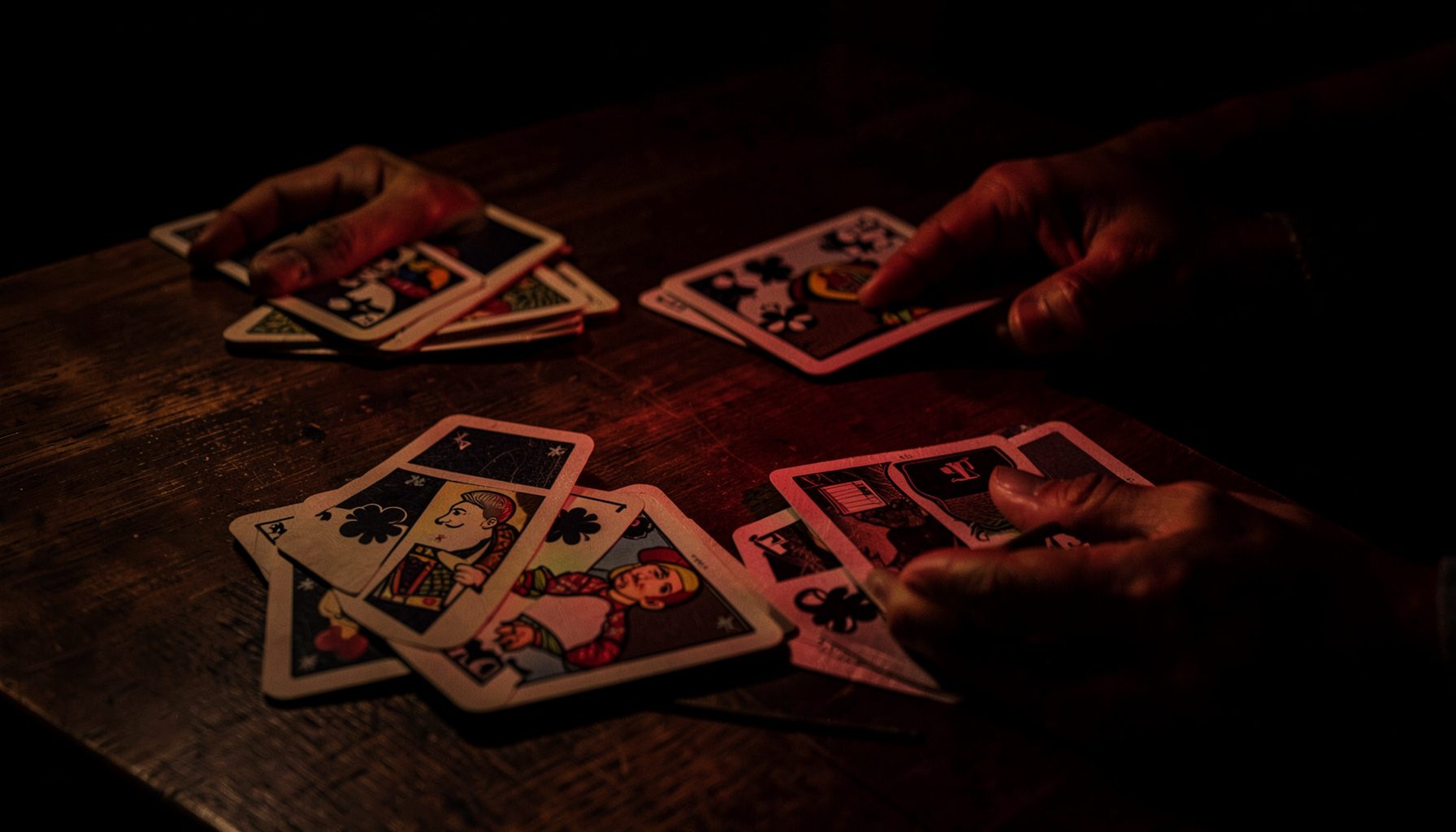 Multiple video poker hands displayed on a dark wooden table with warm side lighting